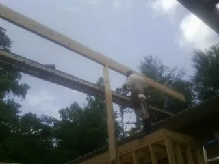 Carpenter setting a ridge beam over a new addition frame — Ice Dam Removal by Roofing Brothers in Meservey