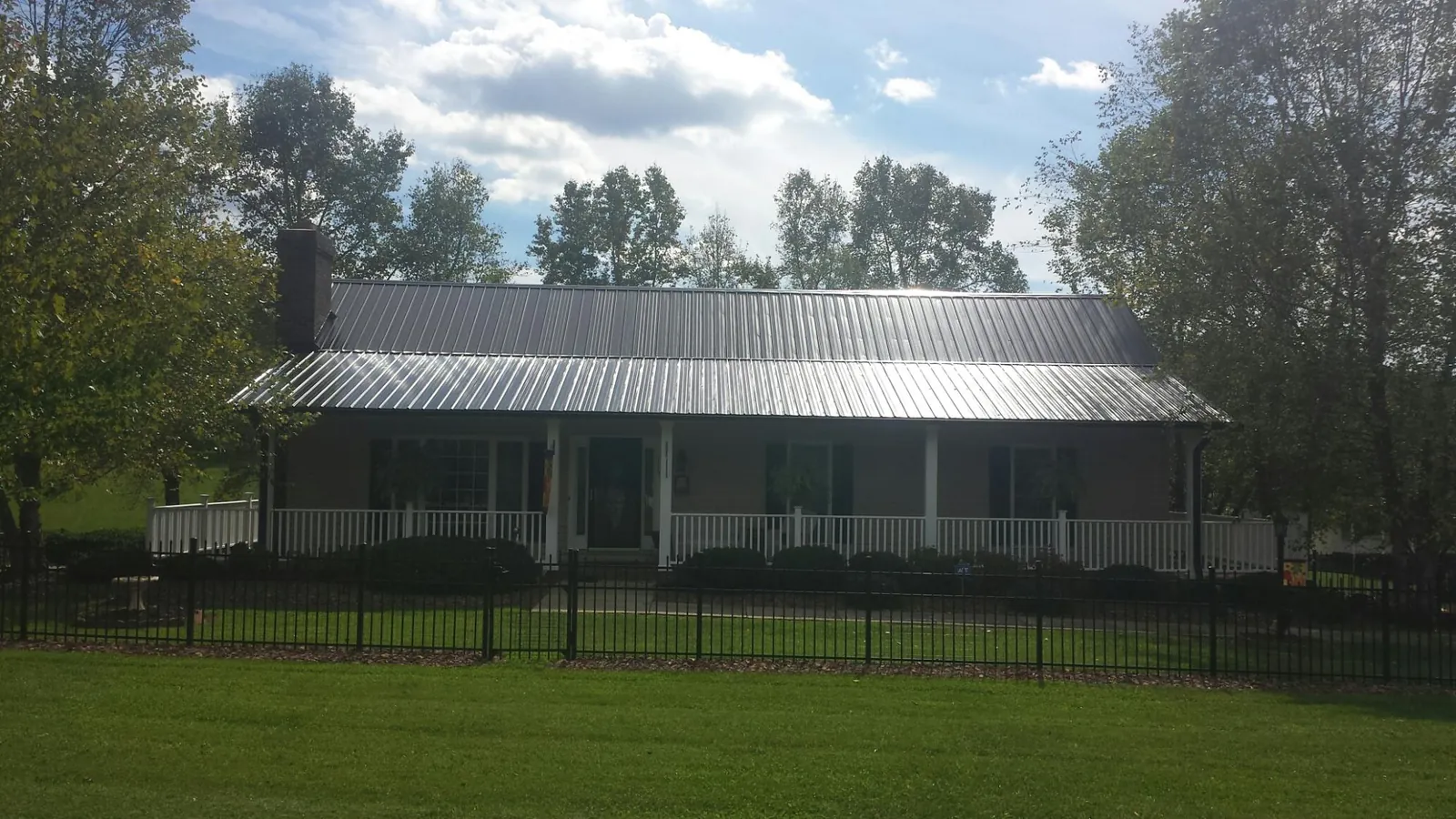 Gray metal roof on a brick ranch with a full width front porch — Gutter Guard Installation work by our crew in Meservey