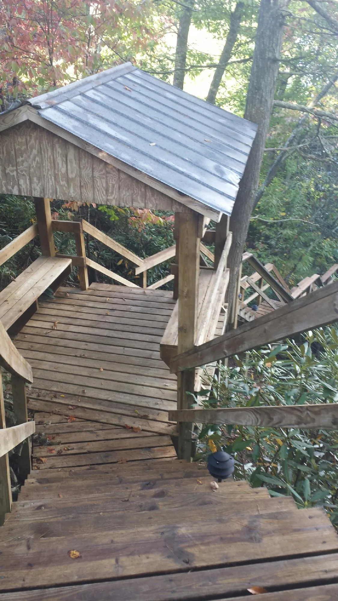Metal roofed shelter over wooden steps on a wooded walkway — Skylight Repair & Installation work by our crew in Meservey